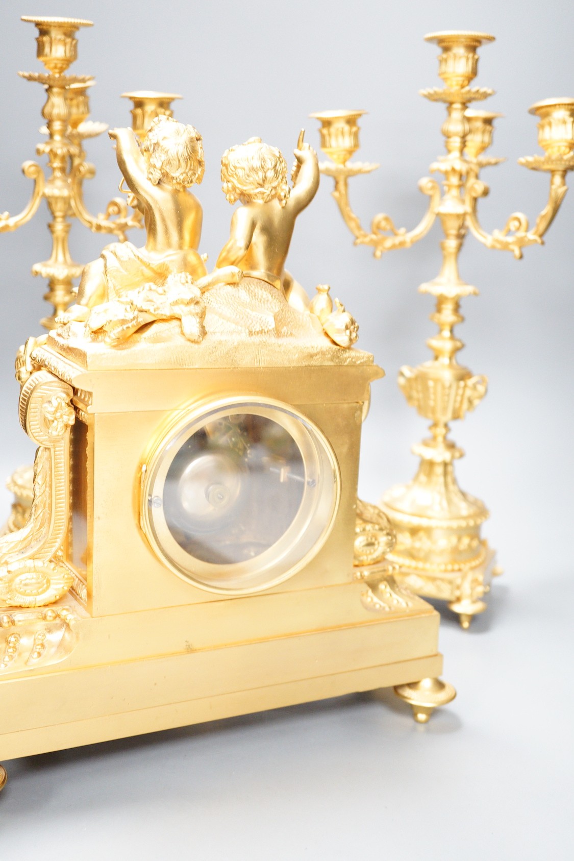 A Louis XVI style ormolu ‘cherub’ clock garniture, late 19th century, with pendulum, 43cm tall